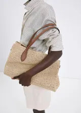 Bolso tipo tote de tejido de fibra natural en color beige, con doble asa larga de hombro en cuero sintético marrón.