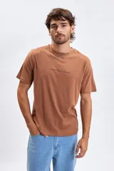 Remera de manga corta color marrón tostado, con cuello redondo y estampa minimalista con texto en el pecho.
