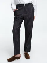 Pantalon de corte recto y tiro medio confeccionado en denim de algodon con textura suave. Presenta cierre frontal con boton y bolsillos laterales.