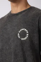 Remera oversize de algodón con efecto lavado gastado, cuello redondo y mangas cortas. Presenta un diseño circular estampado en el pecho con el texto VCP CONCEPT STUDIO.