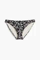 Bombacha de bikini tipo vedetina de cintura media y cobertura moderada, color negro con delicado estampado floral blanco.