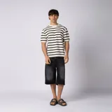 Bermuda de jean baggy color negro con lavado gastado, de corte ancho y largo hasta debajo de la rodilla, con diseño de cinco bolsillos y detalles de recortes en los bolsillos traseros.