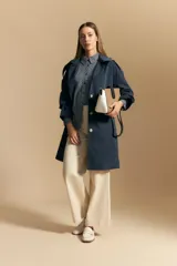 Camisa de manga larga con diseño de rayas verticales en tonos grises y blancos, cuello camisero y cierre frontal con botones.