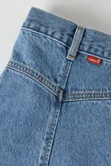 Falda midi de denim en tono azul clásico, con corte evasé, tiro medio, costuras yugulares destacadas y cierre frontal con botones metálicos.