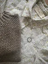 Camisa de lino con estampado floral liberty, cuello clásico, cierre frontal con botones y aplique bordado de flor de encaje en el pecho.