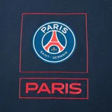 Remera azul marino de algodón con cuello redondo y manga corta. Estampado frontal con el escudo del Paris Saint-Germain y la palabra "Paris" en rojo.