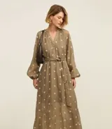 Vestido largo evasê color marrón con estampado de flores blancas, cuello en V, mangas largas abullonadas y cinturón de lazo.