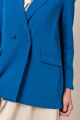 Blazer azul eléctrico de crepe y spandex, corte clásico, con solapas de muesca, cierre cruzado con botones forrados y bolsillos con solapa.