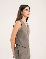 Chaleco de vestir gris oscuro con textura tipo tweed, escote en V y botones frontales. Corte levemente entallado y largo a la cintura.