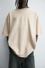 Camiseta color caqui de corte holgado, con cuello redondo y mangas cortas. Acabado con efecto lavado y ruedo irregular.