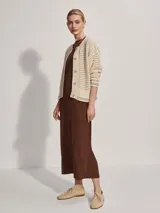 Cárdigan color crema de tejido de punto calado, con cuello redondo, cierre frontal con botones y corte holgado.