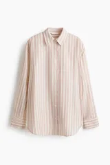 Camisa de corte oversize, con diseño de rayas verticales en tonos rosados, blancos y beiges, cuello clásico, mangas largas con puños abotonados y cierre frontal de botones.