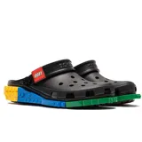 Zuecos Crocs de color negro, en colaboración con Lego, con tira trasera decorada con el logo de Lego y plataforma inspirada en bloques de construcción de colores azul, amarillo y verde.