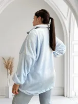 Campera celeste de tela tipo peluche, con cierre frontal, cuello alto y bolsillos con ribete plateado.