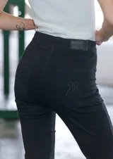 Pantalón jean negro de tiro medio alto y corte oxford con botamanga ancha al corte.