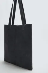 Bolso tipo shopper fabricado en cuero con acabado serraje color gris oscuro. Compartimento principal sin cierre con bolsillo interior con cremallera. Dos asas de mano fabricadas en cuero.
