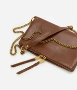 Bolso bandolera de estructura flexible confeccionado en poliuretano color marrón. Presenta correa larga de cadena metálica dorada con apoyo para el hombro, cierre superior con cremallera y tiradores alargados de cuero sintético.
