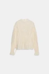 Blusa color crema de algodón con cuello alto, manga larga y bordados florales.