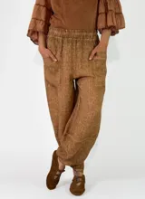Pantalón de lino color amarillo mostaza, de corte bombacho y relajado, con bolsillos delanteros aplicados y cintura elástica.