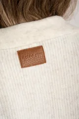 Sweater de punto con cuello polo y cierre frontal de tres botones. Presenta un diseño de corte oversize, mangas largas y textura acanalada.