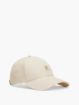 Gorra de béisbol color beige claro, confeccionada en algodón peinado. Presenta el logo de Tommy Hilfiger en dorado en el frente y hebilla metálica ajustable en la parte trasera.