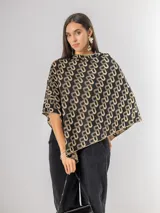 Poncho de tejido liviano con diseño estampado geométrico en tonos negro y beige. Presenta un corte asimétrico y caída fluida.