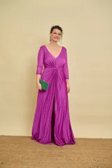 Vestido largo color fucsia, con escote en V pronunciado, detalle de frunce y nudo en la cintura, mangas tres cuartos de tul con apliques brillantes y tajo frontal en la falda.