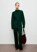 Jersey de punto fino color verde oscuro, con cuello perkins, manga larga y diseño entallado con detalle de lazo anudado en la cintura.