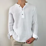 Camisa de muselina blanca de manga larga, con cuello mao y cierre frontal de tres botones. Presenta una textura arrugada característica del tejido.
