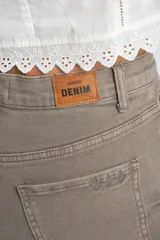 Jean de corte wide leg y tiro medio, en color gris topo. Presenta un diseño de pierna ancha con ruedo desflecado y cierre frontal con botón y cremallera.