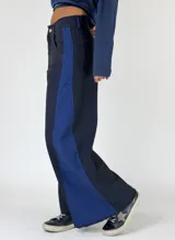 Pantalón de denim azul oscuro con corte ancho y una franja vertical azul en el lateral.