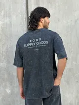 Remera gris con efecto gastado, corte oversize, mangas cortas y estampado en la espalda con el texto "SUPPLY GOODS DESIGNED IN PUNTA DEL ESTE".