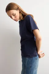 Remera azul marino de manga corta, corte recto y cuello redondo, con detalle de aplicación bordada de flores de crochet en el lateral inferior.
