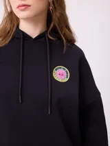 Canguro gris con capucha, de corte oversize, con estampado gráfico multicolor en la espalda que incluye diversos parches y logotipos de la marca Rusty.