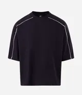 Remera masculina de corte boxy, color negro, con cuello redondo y mangas cortas amplias. Presenta detalles de vivos blancos en contraste a lo largo de las costuras de las mangas y hombros.