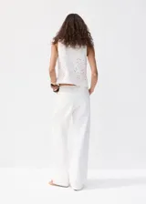 Jeans blancos de silueta balloon, tiro regular y diseño con bordados calados distribuidos en la prenda.