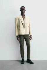 Pantalón chino de corte ajustado, color beige, con bolsillos laterales y bolsillos traseros de vivo. Cuenta con cierre frontal de cremallera y botón.