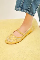 Bailarina negra de estilo plano con tira de terciopelo que cruza el empeine. Presenta bordados intrincados en hilo dorado y apliques de lentejuelas y cuentas en la punta y el cuerpo del zapato.