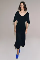 Vestido largo de punto color negro, con escote en V pronunciado tanto en el delantero como en la espalda, y mangas cortas anchas con vuelo.