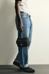 Bandolera de acabado engomado negro con compartimento principal con cierre, bolsillo interior con cierre y bolsillo frontal con solapa y hebilla metálica de liberación rápida. Cuenta con asa de hombro ajustable y extraíble.