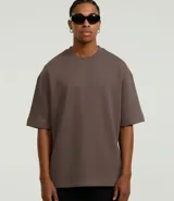 Remera de corte oversize color marrón, con cuello redondo, mangas cortas y sisa desplazada. Diseño liso sin estampados.