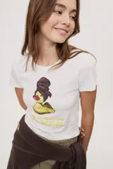 Remera blanca de manga corta, con estampa frontal de un pato de hule con turbante y labios pintados, acompañada de la frase "In all else fails, denial".