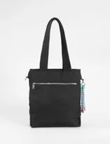 Cartera tipo shopper de color beige con diseño matelaseado de líneas onduladas y costuras en contraste azul. Cuenta con doble asa de hombro y un colgante decorativo de cordones multicolor en uno de sus laterales.