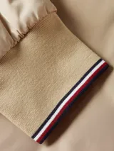 Campera bomber acolchada color beige de poliéster reciclado repelente al agua, con cuello estilo béisbol, cierre de cremallera, puños y cuello de punto canalé, dos bolsillos diagonales en la cintura y detalles distintivos de Tommy Hilfiger.