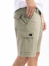 Bermuda de trekking color caqui, corte clásico, con múltiples bolsillos funcionales, incluyendo bolsillos cargo con cierre y botón. Presenta presillas para cinturón y cierre de botón y cremallera.