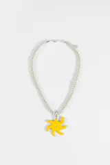Collar de cordón trenzado en color verde menta con dije central en forma de sol amarillo con un pequeño detalle brillante en el centro. Cuenta con cierre de mosquetón y cadena de alargue metálica.