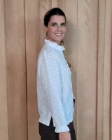 Camisa de manga larga con estampado de rayas verticales en tonos crudo y beige. Presenta cuello alto con volados, cierre frontal con botones dobles y puños con volados.