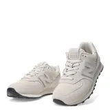 Championes urbanos New Balance modelo 574, color marfil, confeccionados en gamuza y malla con detalles texturizados en la puntera. Presentan el logo N característico en los laterales y suela con diseño moteado.