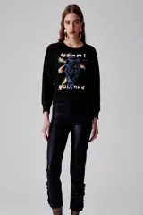 Pantalón de tiro medio color negro metalizado, de calce recto y detalle de volados en la botamanga.