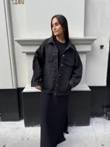 Campera clásica de jean negra con cuello camisero, bolsillos frontales y detalles de brillos plateados.